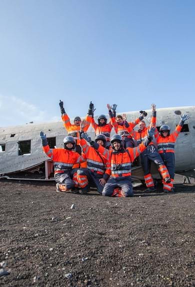 A group of ATV riders posing in front of the famous plane wreck in Iceland
