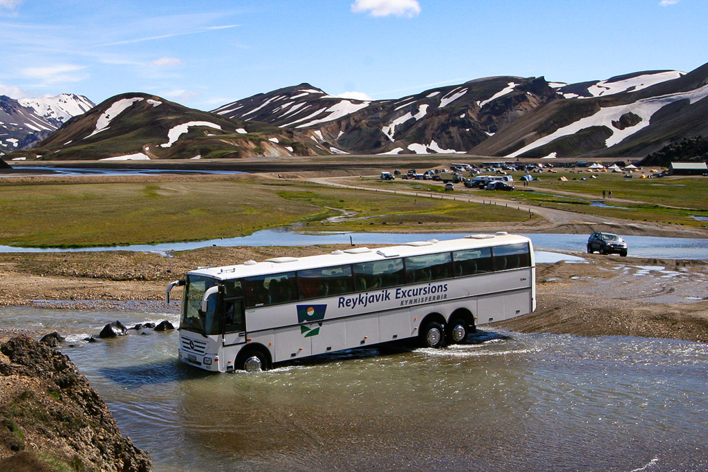 A large modified bus crosses the  river at landmannalaugar