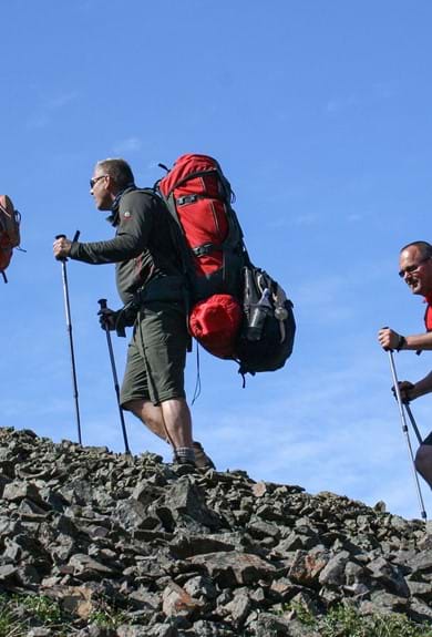 three hikers with backpacks walking uphill