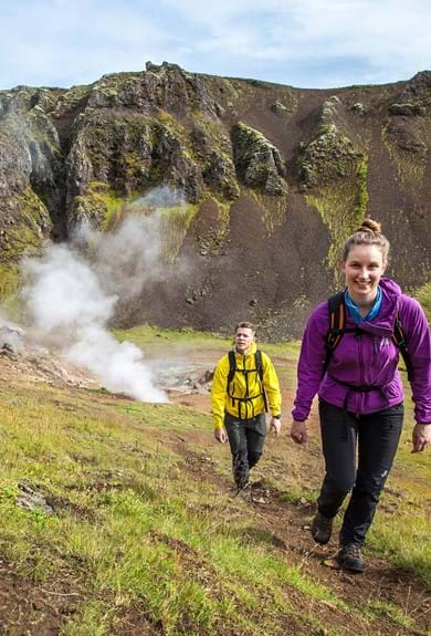 A couple hiking up in the green and hilly nature of Iceland near not springs 
