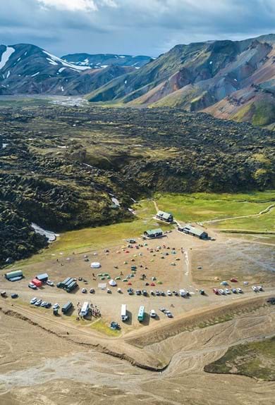 View of Landmannalaugar nature reserve in Iceland, camp site, huts and the lava-field in the background